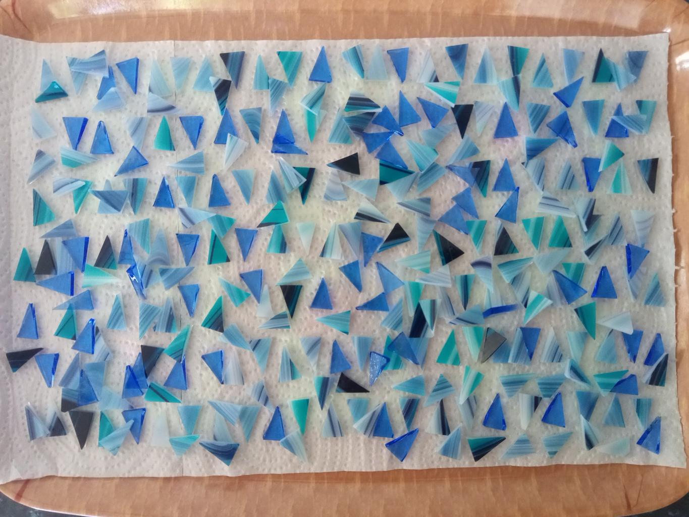 Photo of a tray full of blue glass triangles, cut and washed, ready to assemble into hedgehogs